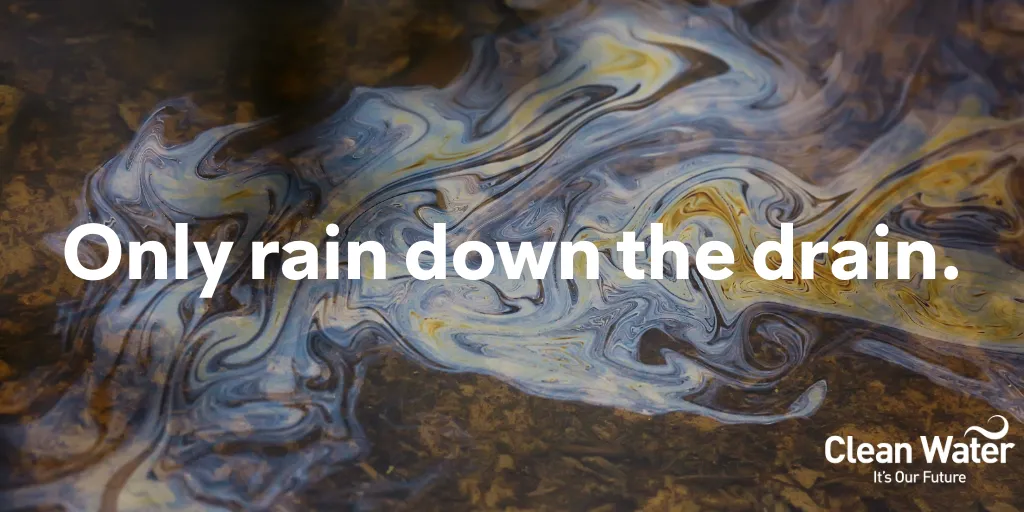 Photograph of motor oil in a puddle of water in the road with text across the image, “Only rain down the drain”.