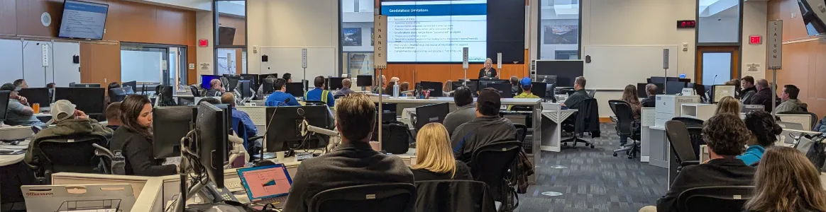 Photograph of regional water provider staff gathered in a large room, looking towards a screen with information about regional interconnections